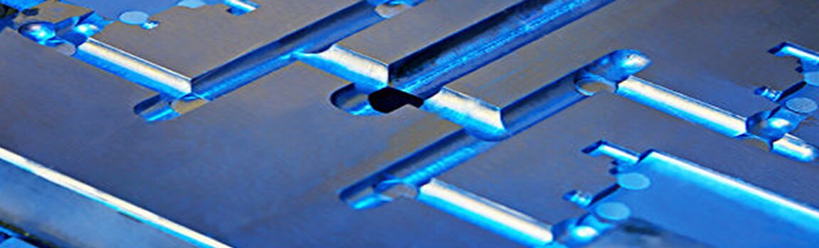 Close-up of a machined steel mold cavity with blue-anodized runners