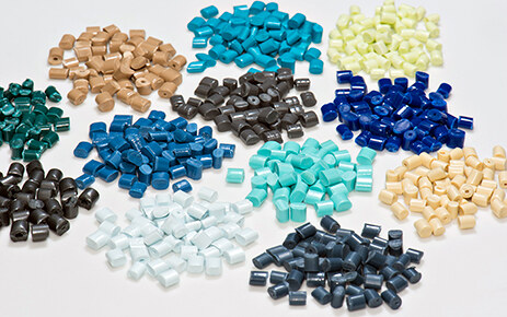 Piles of resin pellets in tan, blue, black, white and grey